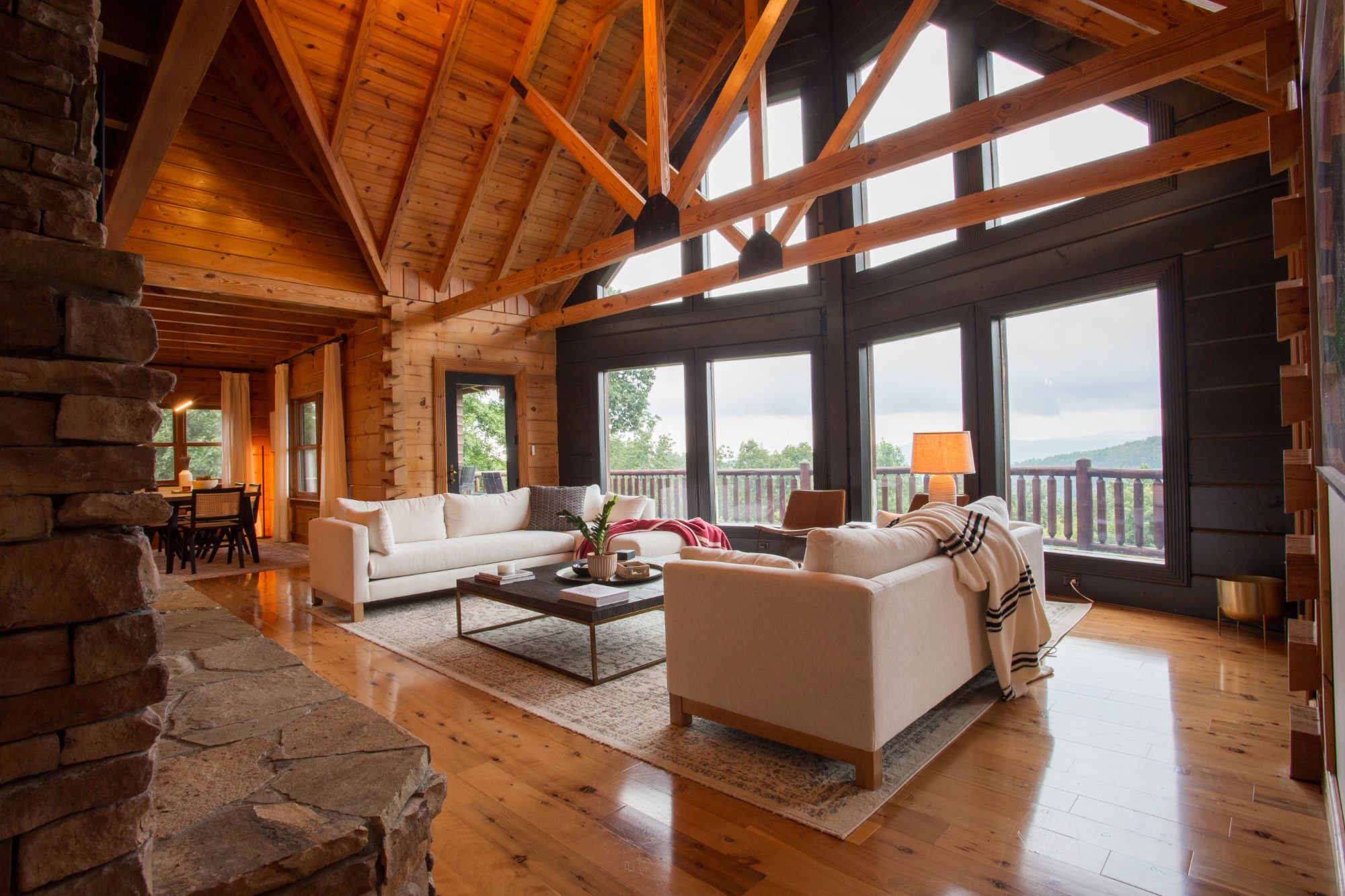 The Ridge great room — vaulted log ceilings, stone fireplace, and floor-to-ceiling mountain views