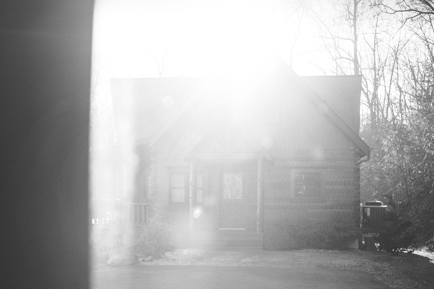 The cabin at sunrise, morning light flaring through bare trees