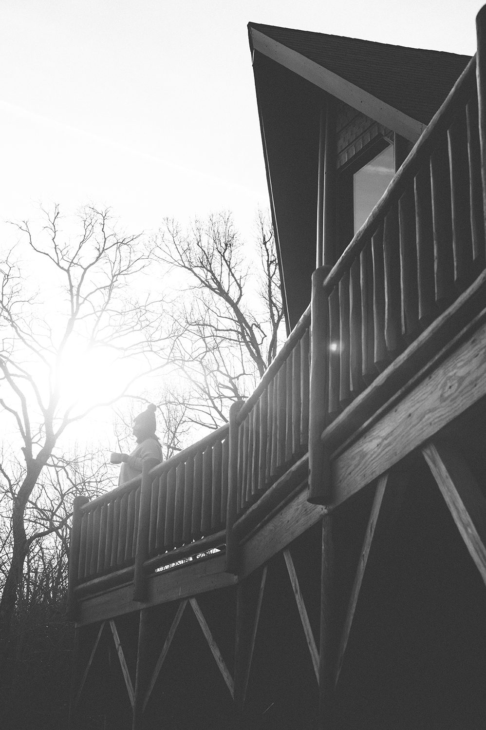 A silhouette leaning on the balcony rail against the winter sun